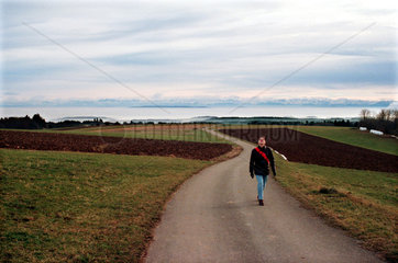 Spaziergaengerin inmitten von Feldern in Hoechenschwand  Deutschland