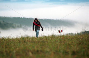 Frau geht spazieren in nebelverhangener Schwarzwaldlandschaft  Hoechenschwand  Deutschland