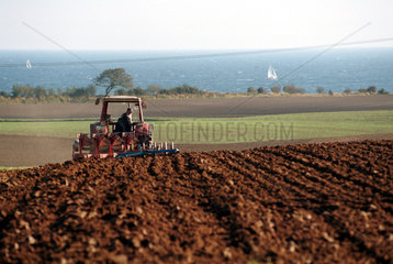 Ein Landwirt pfluegt mit einem Traktor sein Feld  Schoenhagen  Deutschland