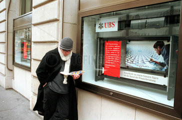 Mann neben Werbung der Schweizer Bank UBS  Basel  Schweiz