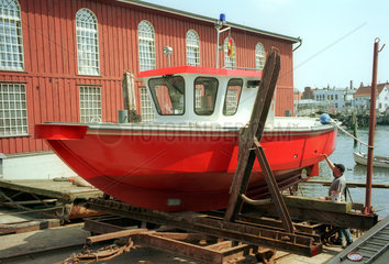 Ein an Land liegendes Feuerwehrboot  welches gerade gestrichen wird