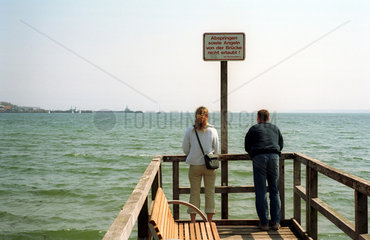 Ein Paar steht auf einem Steg und blickt auf die Ostsee