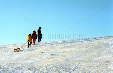 Pilsum  drei Menschen klettern den verschneiten Deich hoch