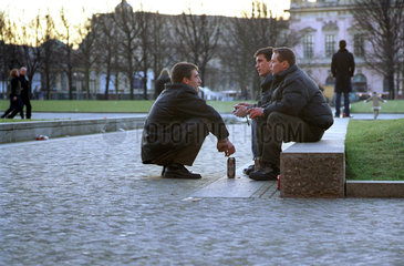 Berlin  drei junge Maenner sitzen auf Steinen im Lustgarten
