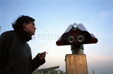 Junge  rauchende Frau neben einem Muenzfernglas