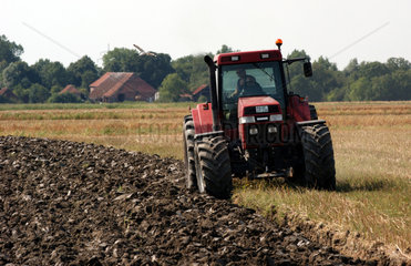 Bauer im Traktor pfluegt sein Feld