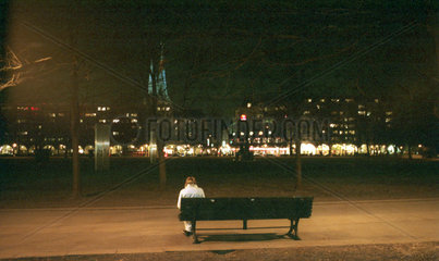 Eine Frau sitzt allein im Dunkeln auf einer Parkbank