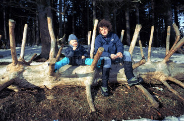 Vater und Sohn sitzen auf einem Baumstamm