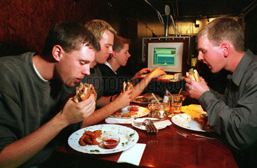 Berlin  Deutschland  Jungen essen und surfen im Internetcafe