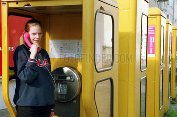 Berlin  Deutschland  Maedchen telefoniert in einer oeffentlichen Telefonzelle
