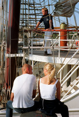 Rostock  ein Paerchen sitzt vor einem Boot am Wasser