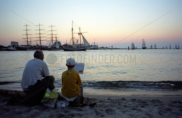 Warnemuende  Vater und Sohn sitzen abends am Strand