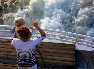 Warnemuende  eine Frau mit Kind steht am Heck eines Schiffes