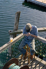 Bar Harbor  USA  ein aelterer Mann trinkt ein Bier im Hafen von Mount Desert Island
