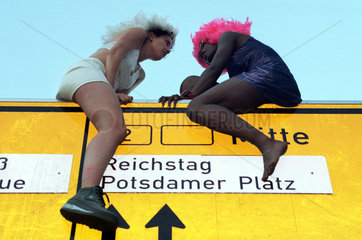 Berlin  Deutschland  zwei Maedchen sitzen auf einem Strassenschild