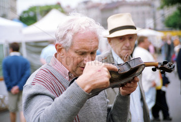 Wien  Oesterreich  Mann prueft eine Geige auf dem Flohmarkt