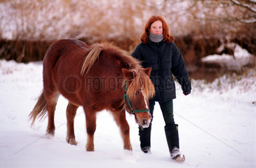 Bremen  Deutschland  Maedchen fuehrt ihr Pony im Schnee spazieren