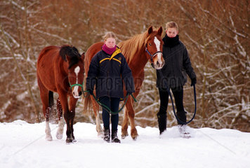 Bremen  Deutschland  Maedchen spazieren mit Pferden im Schnee