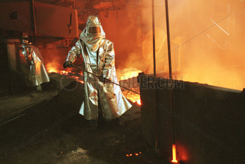 Eisenhuettenstadt  Deutschland  Stahlarbeiter ueberpruefen das Roheisen beim Abstich