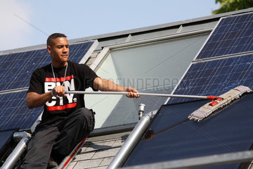 Berlin  Deutschland  Auszubildender putzt ein Solarpanel
