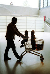 Silhouette eines Vaters mit Kindern im Einkaufskorb
