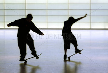 Silhouetten von zwei Jungen auf einem Skateboard