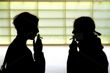 Silhouetten von zwei rauchenden Maedchen