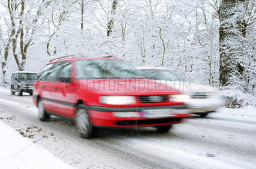 Autos faehren in einer verschneiten Allee