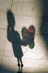 Schatten eines kleinen Maedchens mit Luftballons