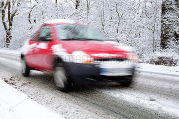 Auto faehrt in einer verschneiten Allee