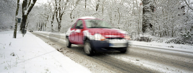 Auto faehrt in einer verschneiten Allee