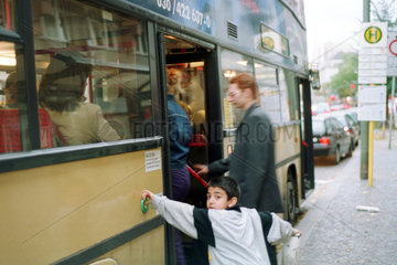 Berlin  Deutschland  kleiner Junge drueckt den Tuerknopf eines Busses