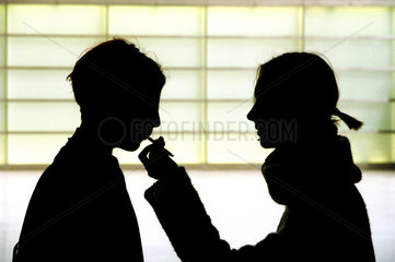 Silhouetten von zwei Maedchen mit einer Zigarette