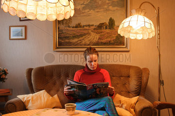 Junge Frau liest in einem Wohnzimmer mit alten Moebeln