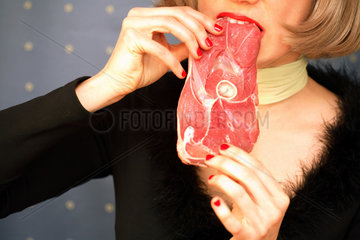 Mund einer Frau beisst in rohes Fleisch