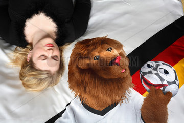 Schlafende  junge Frau mit WM Maskottchen Goleo auf der Bettwaesche