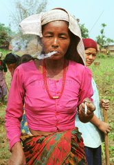 Alte Dame raucht eine Zigarette in Nepal