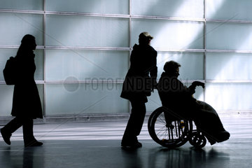 Silhouette einer Frau im Rollstuhl und ihrer Betreuerin