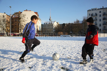 Jungen spielen Fussball im Schnee in Berlin
