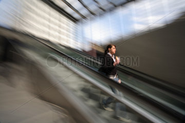 Junge Frau faehrt auf einer Rolltreppe hinab