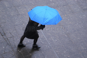 Frau unter einem blauen Regenschirm