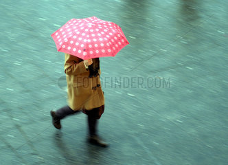 Spaziergaenger unter einem roten Regenschirm