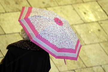 Rentnerin unter einem Regenschirm