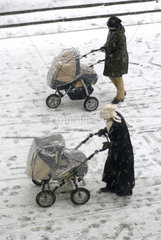 Zwei Frauen schieben ihre Kinderwagen im Schnee