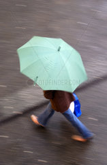 Spaziergaenger unter einem gruenen Regenschirm