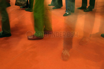 Beine und Fuesse wartender Leute auf rotem Teppich
