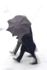 Spaziergaenger mit einem Regenschirm im Schnee
