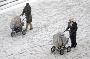 Zwei Frauen schieben ihre Kinderwagen im Schnee