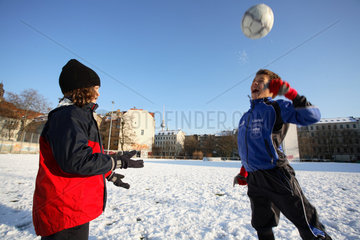 Jungen spielen Fussball im Schnee in Berlin