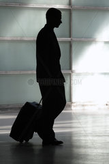 Silhouette eines jungen Mannes mit Koffer